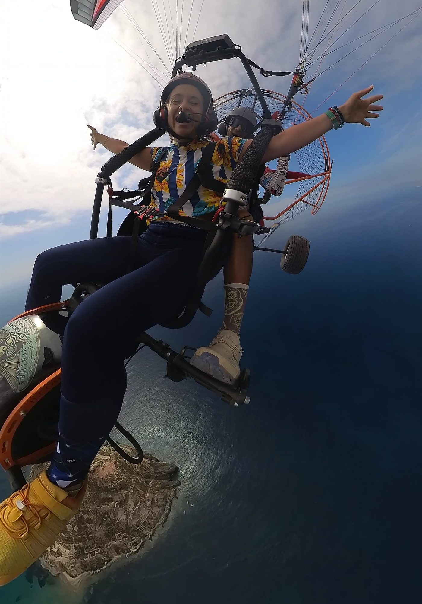 Pasajera volando en tándem con los brazos abiertos sobre el mar