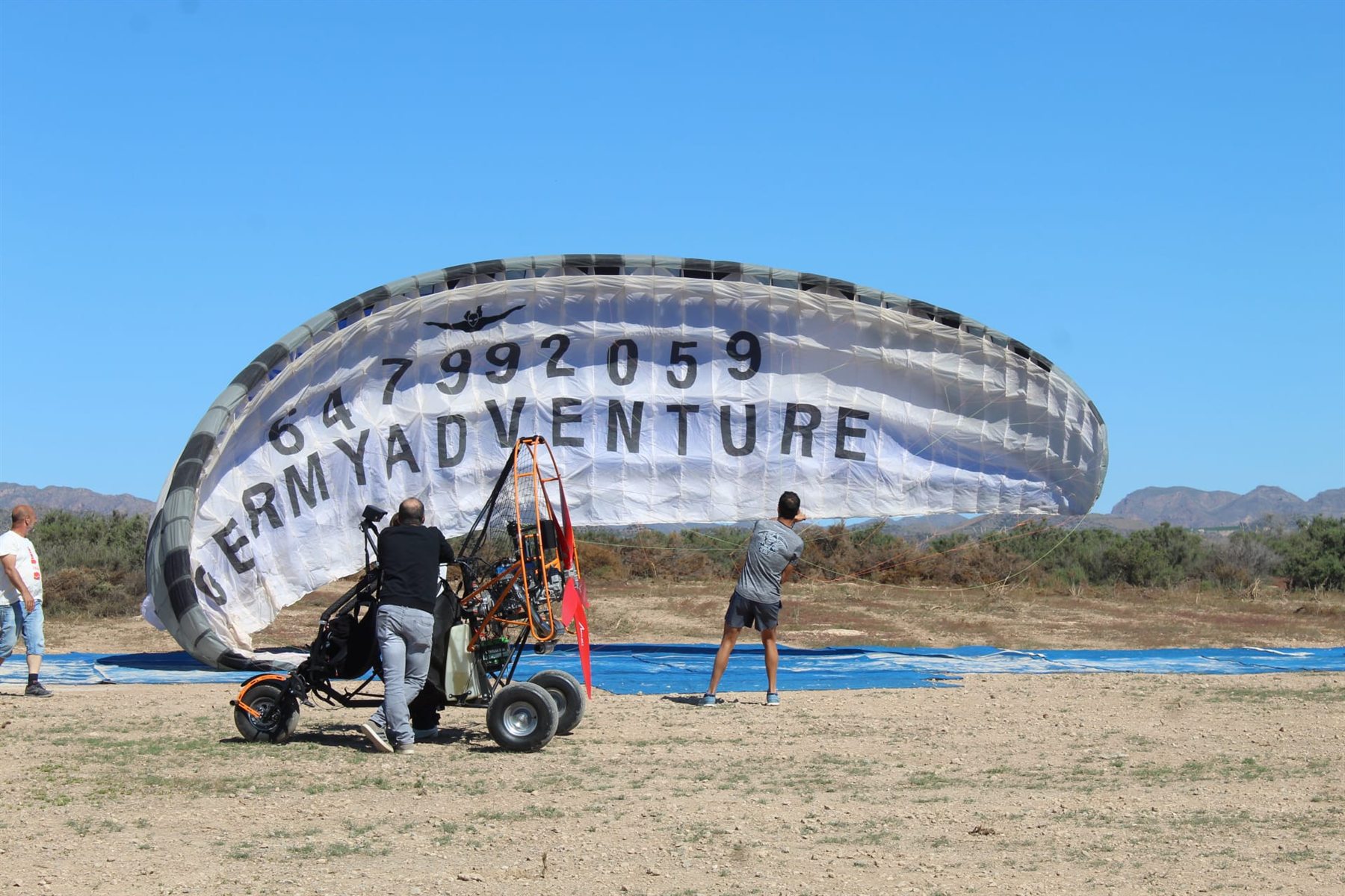 La vela del paramotor hinchada en la campa, con el rótulo Germyadventure